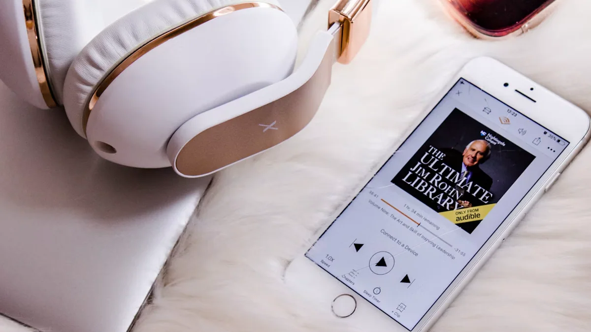 Audibleの再生画面を表示したスマートフォンとヘッドホンの実写写真